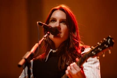Person playing guitar and singing on stage