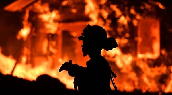 An inmate firefighter monitors flames as a house burns in the Napa wine region in California on October 9, 2017, as multiple wind-driven fires continue to whip through the region. 