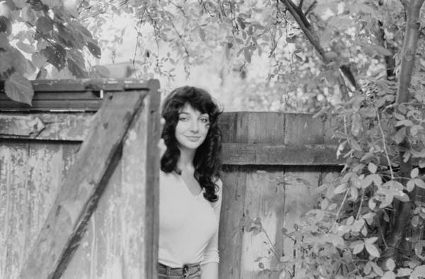 Kate Bush looking through an open gate.
