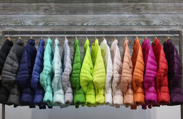 a variety of different colored coats hanging on a rack
