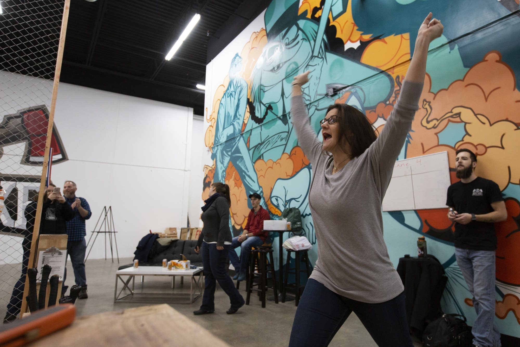 Sarah Hanson cheers as she makes the bullseye at Bad Axe Throwing.