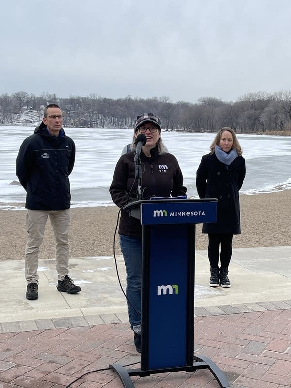 three officials speak at a press conference at a lake