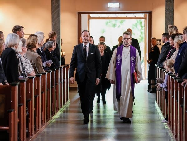 Several people walk down the aisle of a church