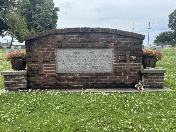 A sign made of brick and stone stands in a field.