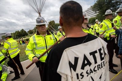 A state trooper stands in front of a tipi.