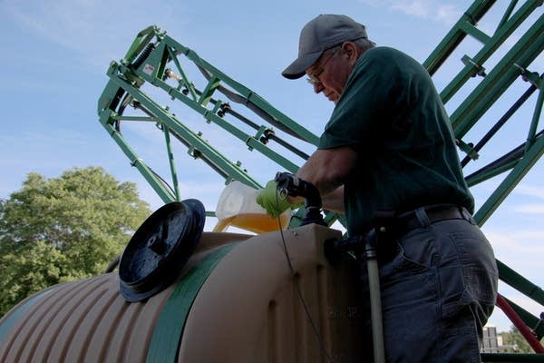 John Draper pours glyphosate into the tank of his sprayer.