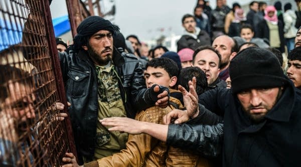 Refugees push each other as they wait for tents. 
