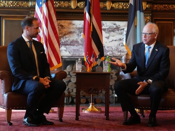 Two men have a conversation while seated in chairs