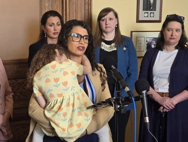 woman speaking into mic holding a child