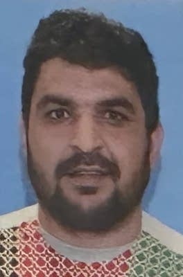 A headshot of a man against a blue background.