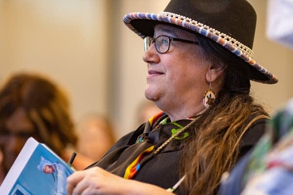 A woman looks up as she listens to a speaker