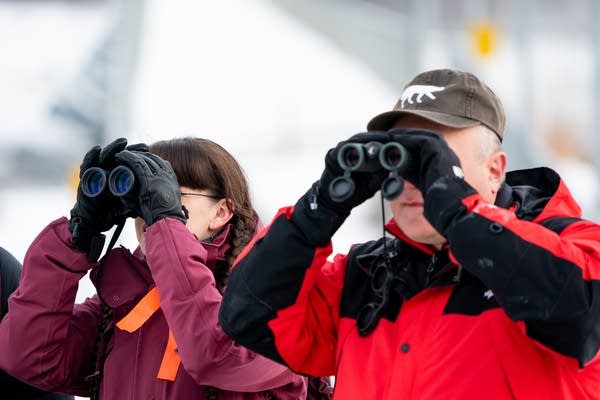 Two people look through binoculars.