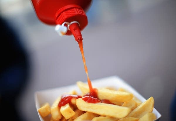 A supporter pours ketchup on his fries. (Photo by Richard Heathcote/Getty Images)