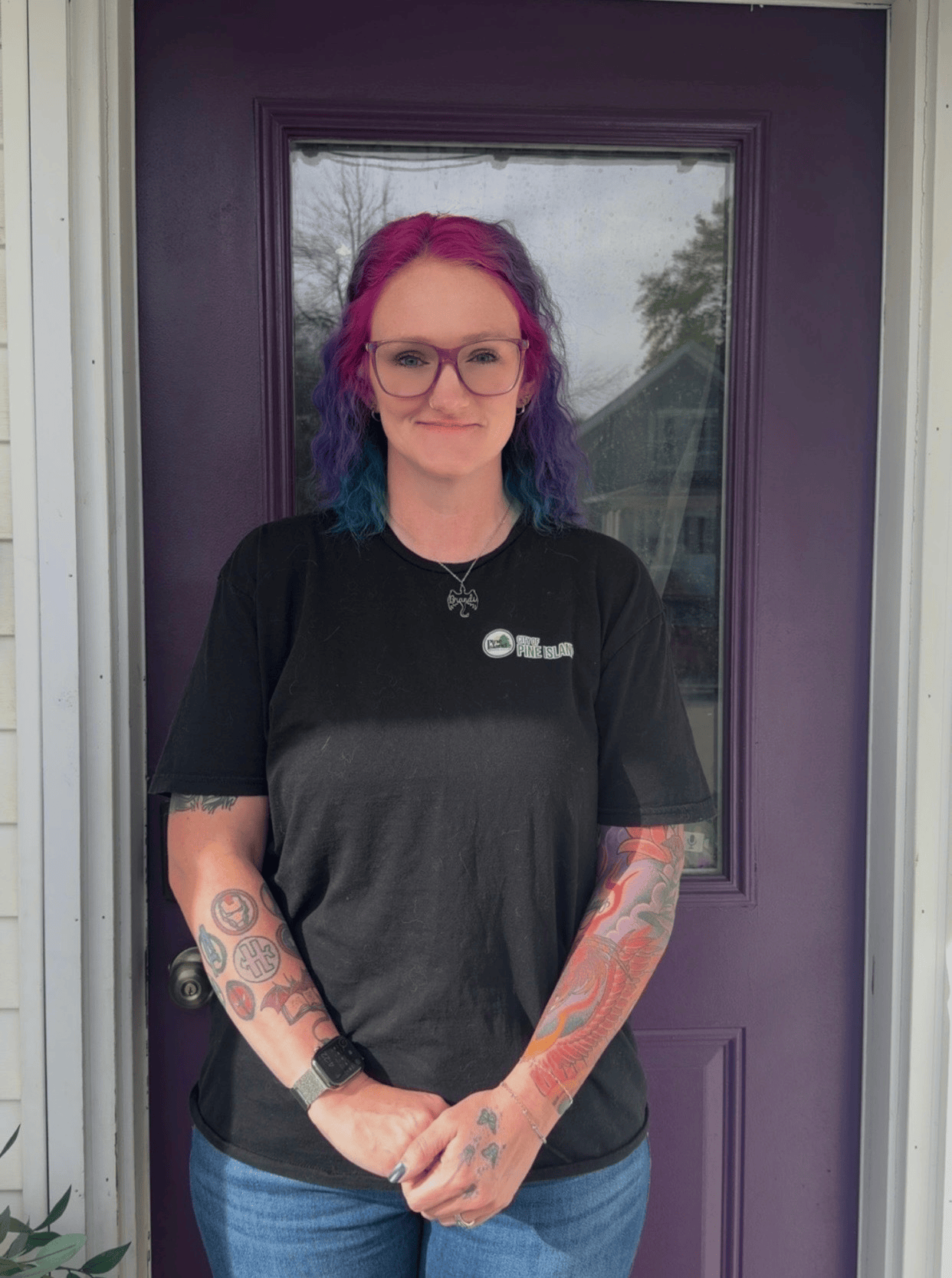 A woman in a black shirt poses for pic in front of purple door