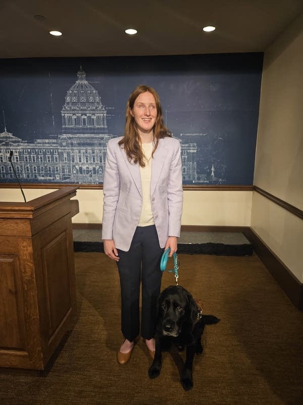 Woman stands near podium with dog on leash