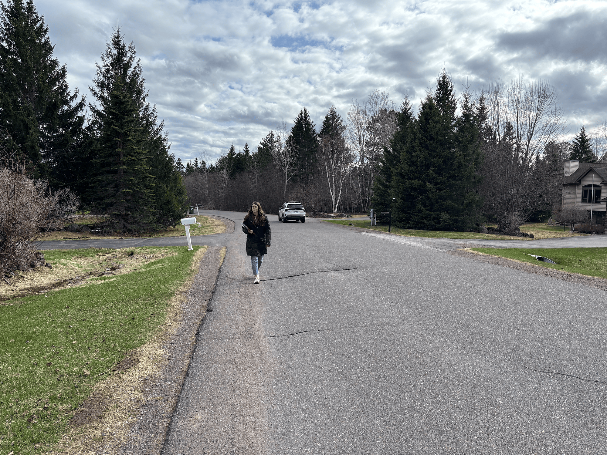 A wide shot of a woman walking down a residential street.