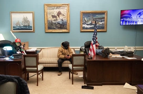 U.S. Capitol rioters sit at the desks in the office of House Speaker Nancy Pelosi in Washington, D.C., in Jan. 6.