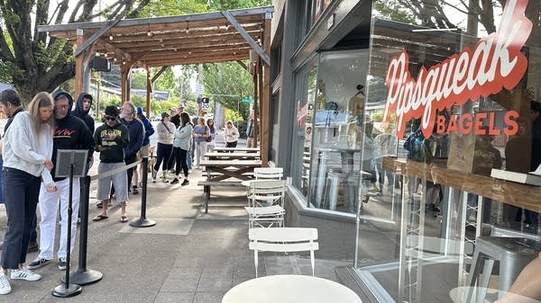 A line of people outside a bagel shop.