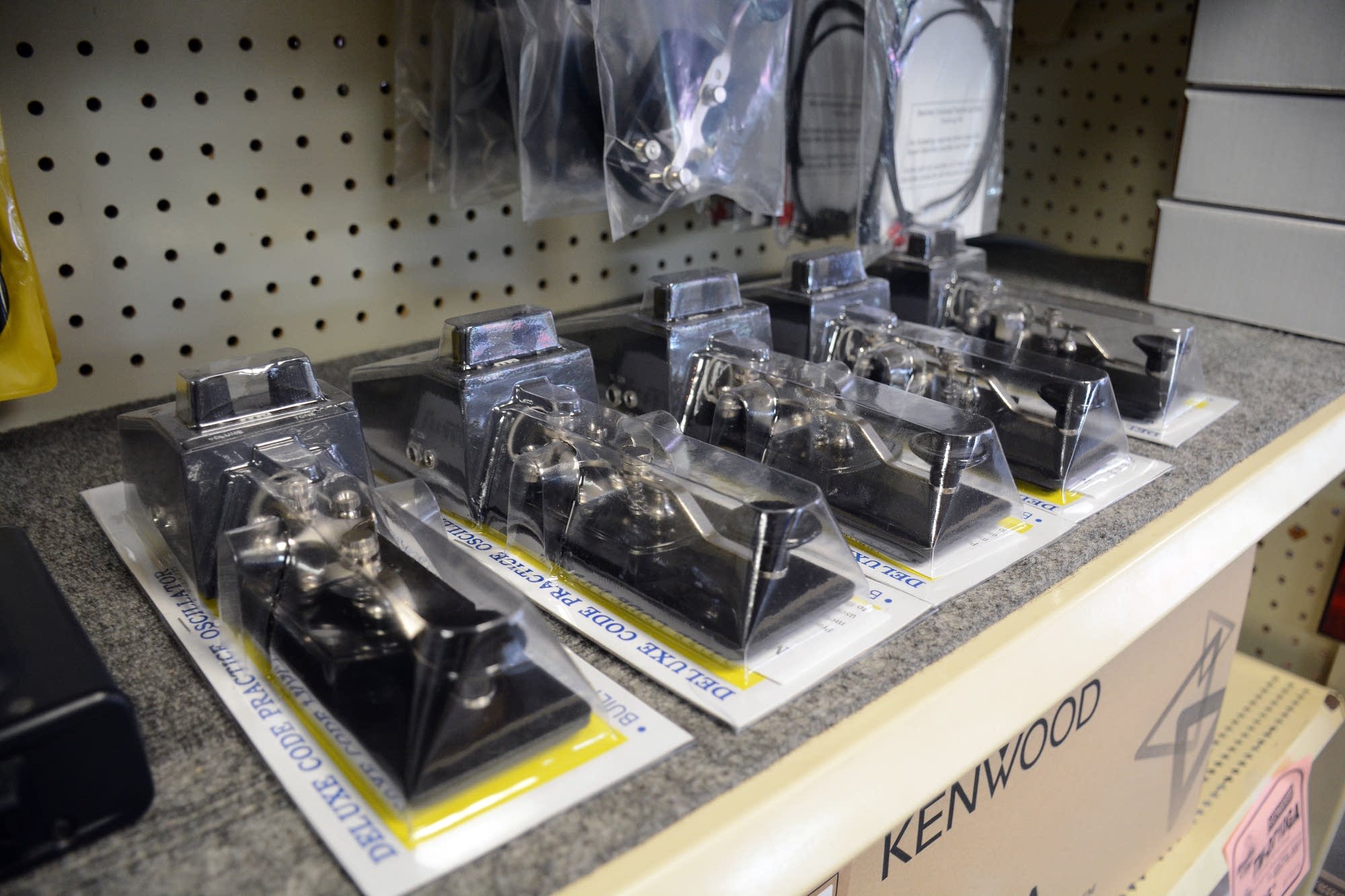 Morse code practice keys are still lined up on the shelf.