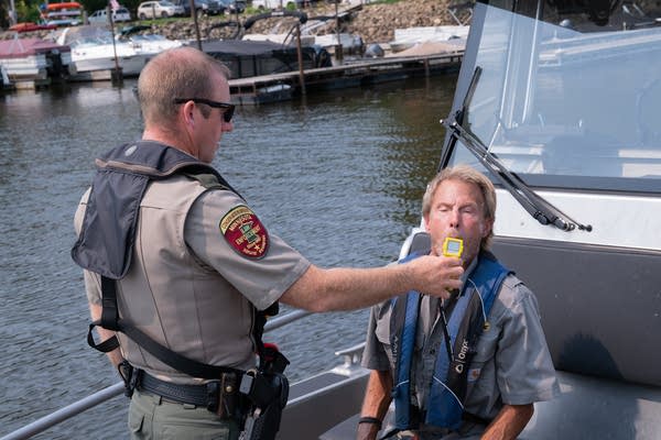 A DNR officer gives a person a field sobriety test on a boat.