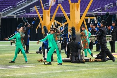 A marching band performs on the field of a football stadium.