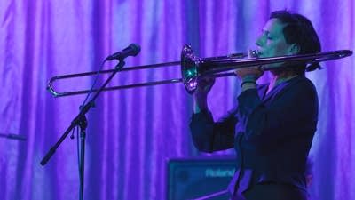 A musician plays trombone onstage in a music venue