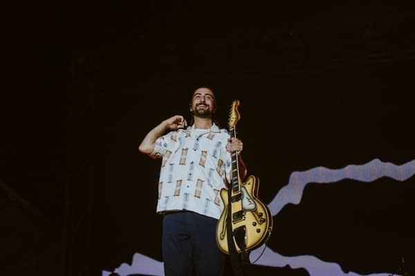 A man with a guitar smiles to the audience