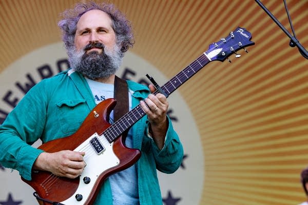 A musician smiles and plays guitar onstage