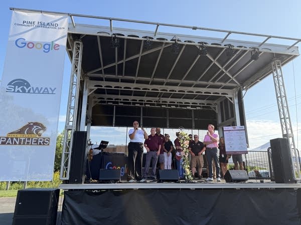 People on a stage speaking outside