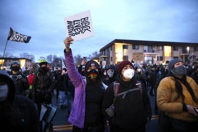 Demonstrators hold signs and flags. 