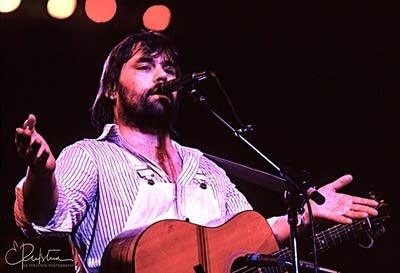 A man with a guitar singing onstage