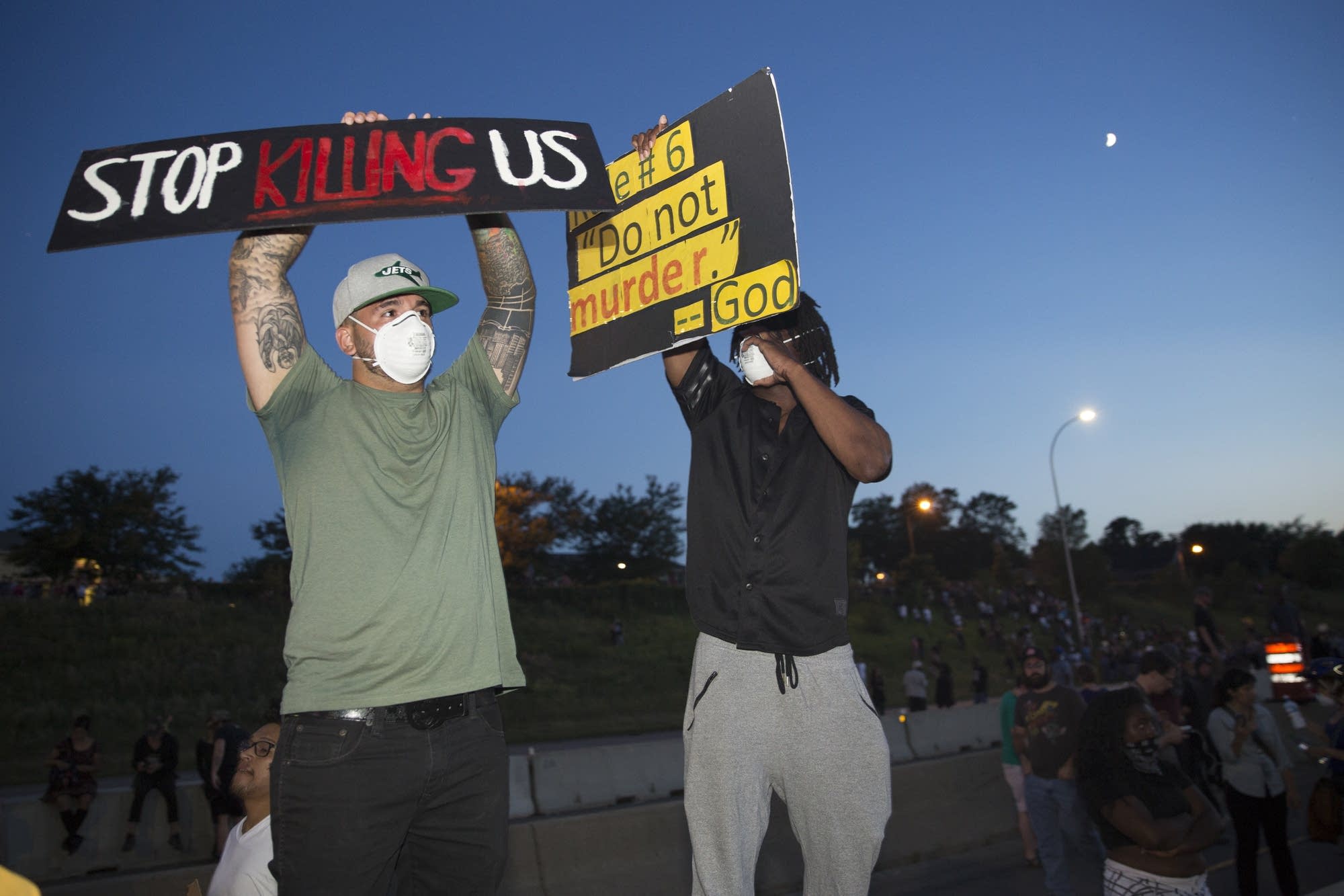 Protesters stand on the concrete barrier.