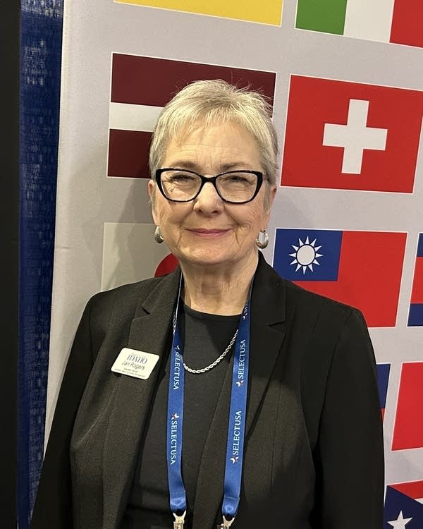 A woman with grey hair in black glasses, a black blazer, and black shirt.