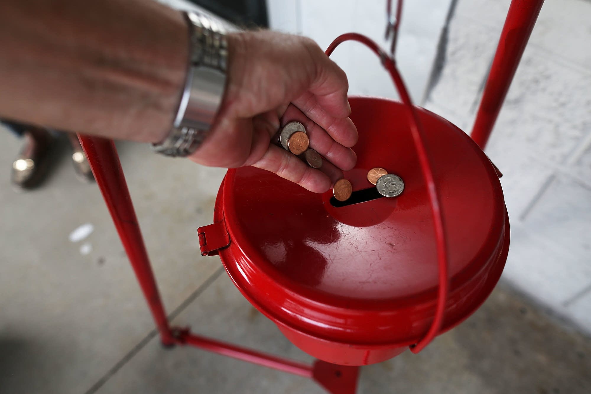 A donation is made into a Salvation Army red kettle.