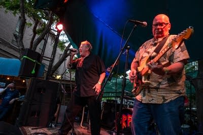 A rock band performing on an outdoor stage