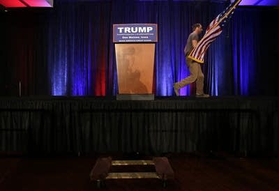 A worker takes down the flag after Trump rally.