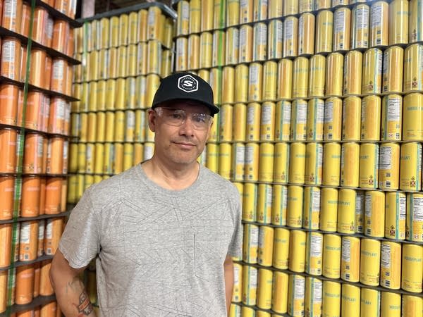 Man stands next to tower of drinks