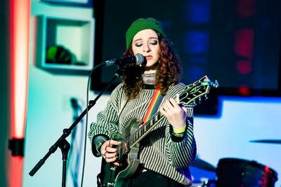 A musician sings and plays guitar onstage