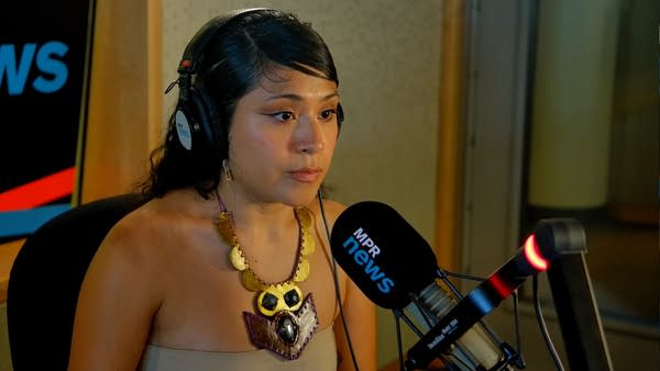 A woman sits behind a mic