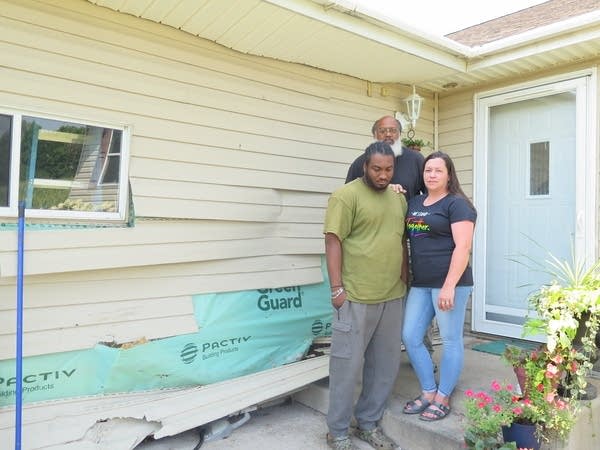 people stand outside of a damaged home