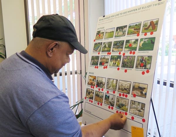 A man puts a sticker on a board with pictures of apartment features. 