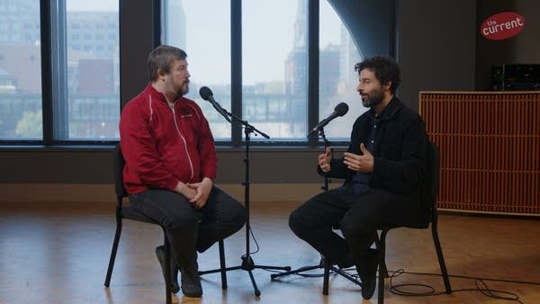Two men have a conversation in a recording studio