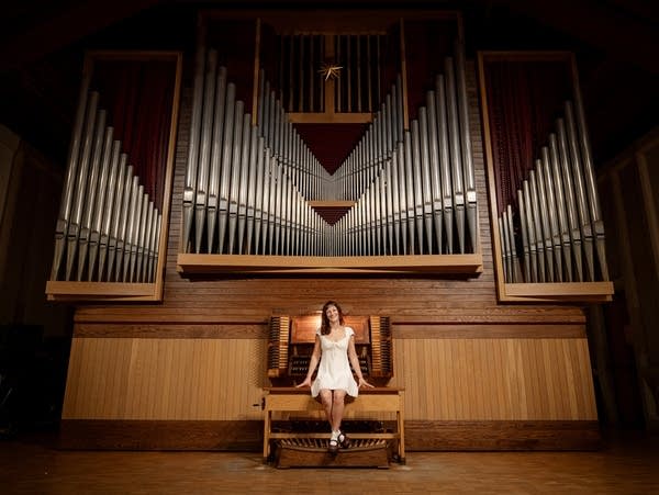 Agnes Barthel wears a dress and sits at an organ.