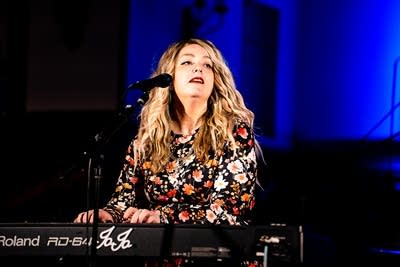 A musician sings and plays keyboards onstage