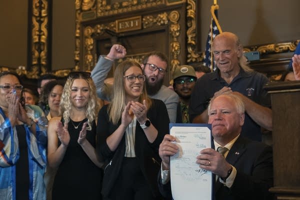 Tim Walz holds up the bill 