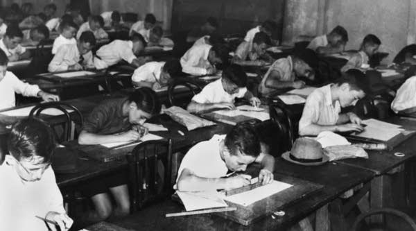 Children sitting at their school desks in a classroom doing scholarship examinations, April 16, 1940.