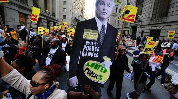 Activists march down Wall Street holding a cutout of JP Morgan CEO Jamie Dimon, during a protest against budget cuts and bank practices, in New York, May 12, 2011. Now, the FBI is launching a preliminary investigation in the company for possible criminal activity.