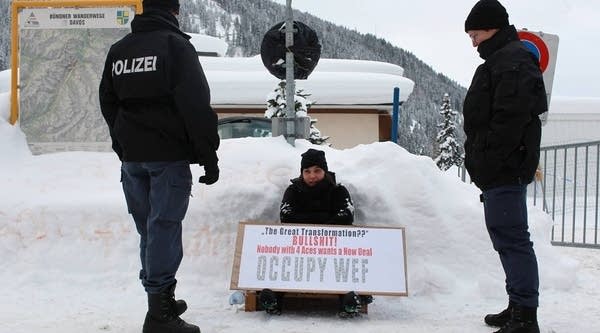 Swiss riot police men frame an Occupy protester in front of the main gate to Davos congress center on January 25, 2012 in Davos, Switzerland. Discussions at the WEF have centered around near and long term problems.