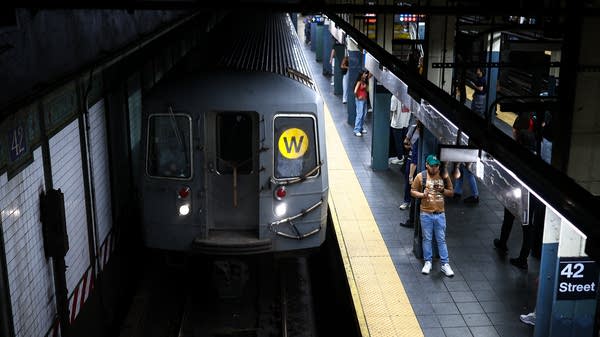 People wait for a W subway.