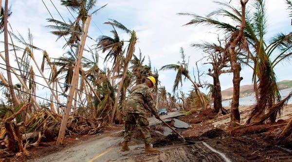 A Puerto Rico National Guard personnel shoves dirt from a damaged road in the aftermath of Hurricane Maria in Humacao, Puerto Rico on October 2, 2017.